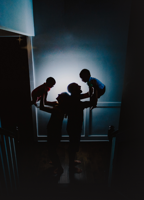 Charlie playing with her two kids on a dimly lit staircase